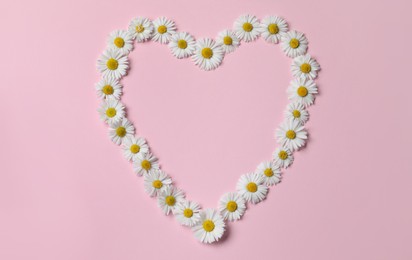 Photo of Heart shaped frame of daisy flowers on pink background, flat lay. Space for text