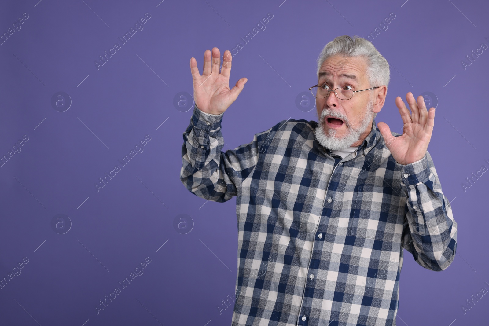 Photo of Portrait of surprised senior man on violet background, space for text