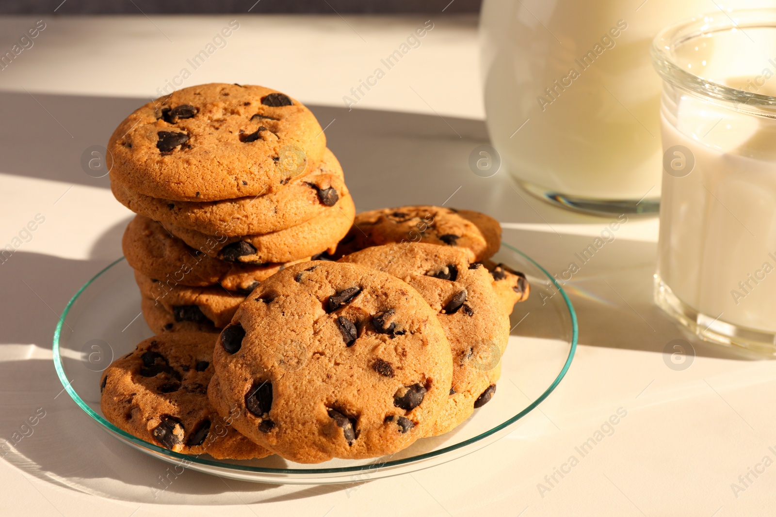 Photo of Delicious chocolate chip cookies and milk on white marble table