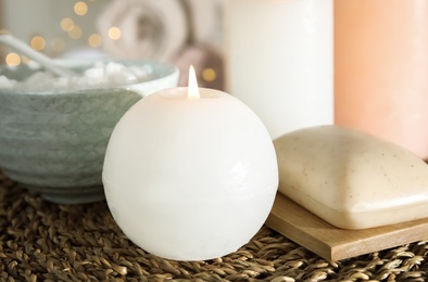 Spa composition with candle on wicker mat, closeup