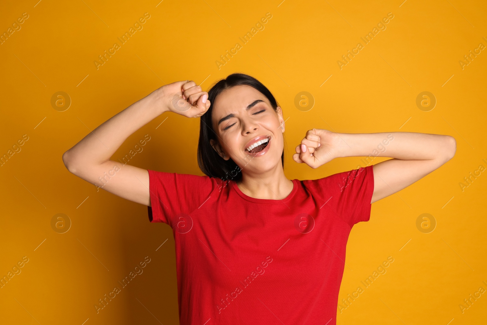 Photo of Young tired woman yawning on yellow background