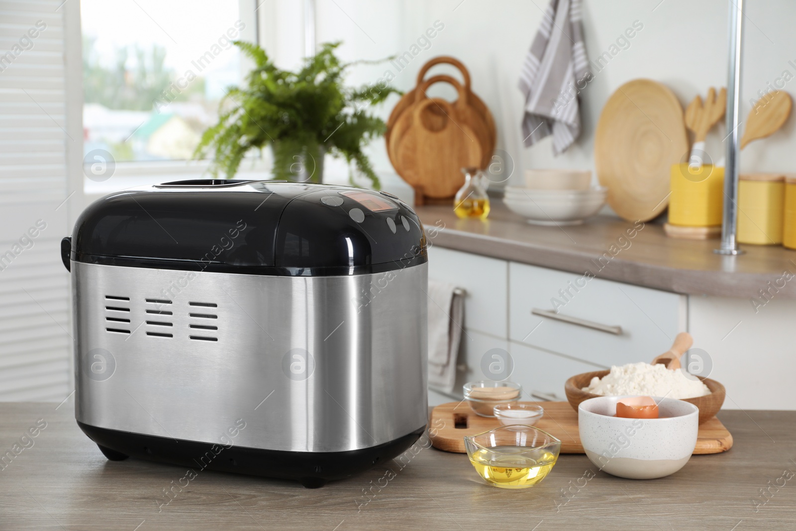 Photo of Breadmaker and products on wooden table in kitchen