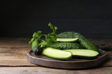 Photo of Fresh ripe cucumbers and parsley on wooden table. Space for text