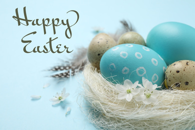 Colorful eggs in decorative nest and text Happy Easter on light blue background, closeup