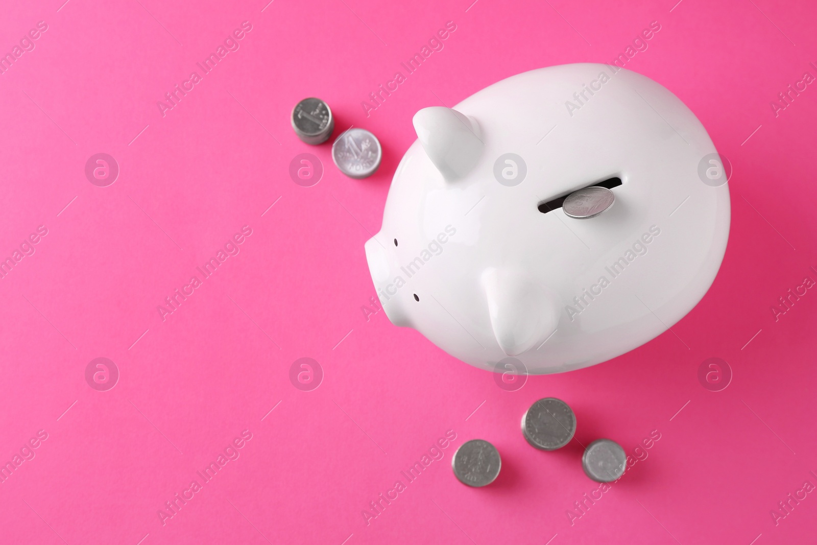 Photo of Financial savings. Piggy bank and coins on pink background, flat lay with space for text