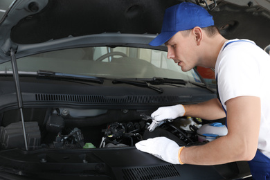 Professional auto mechanic fixing modern car in service center