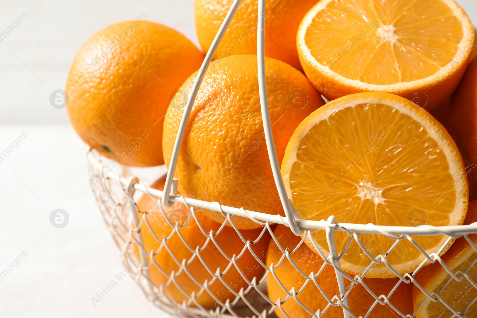 Photo of Basket with ripe oranges on light background, closeup