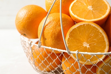 Photo of Basket with ripe oranges on light background, closeup