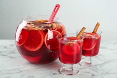 Photo of Glasses and bowl with aromatic punch drink on white marble table