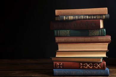 Collection of different books on wooden table against dark background. Space for text