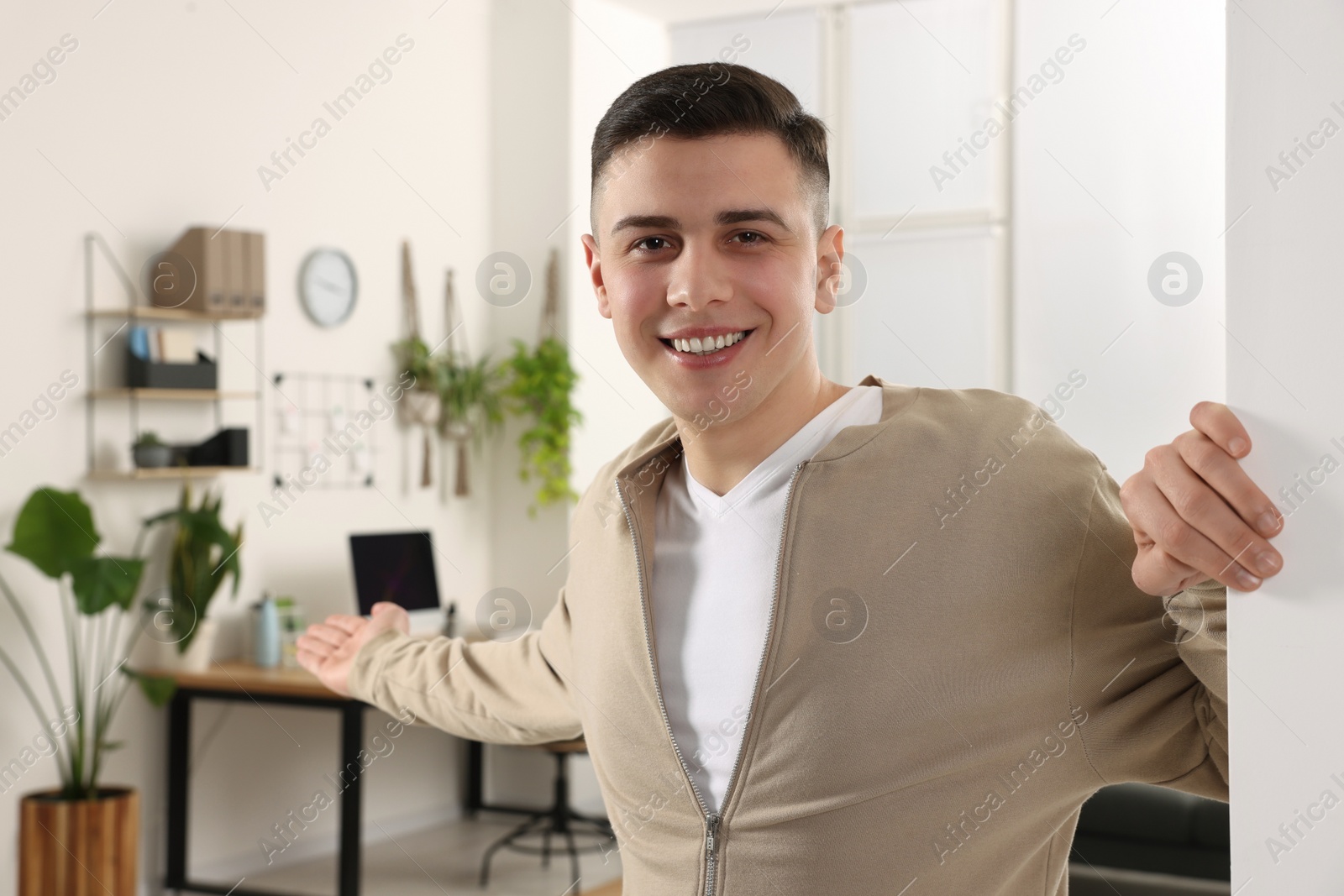 Photo of Handsome man inviting to come in room at home