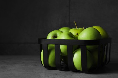 Black metal container full of apples on table against dark grey background, space for text