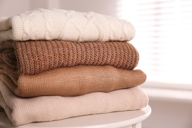 Photo of Stack of folded warm sweaters on white table indoors, closeup