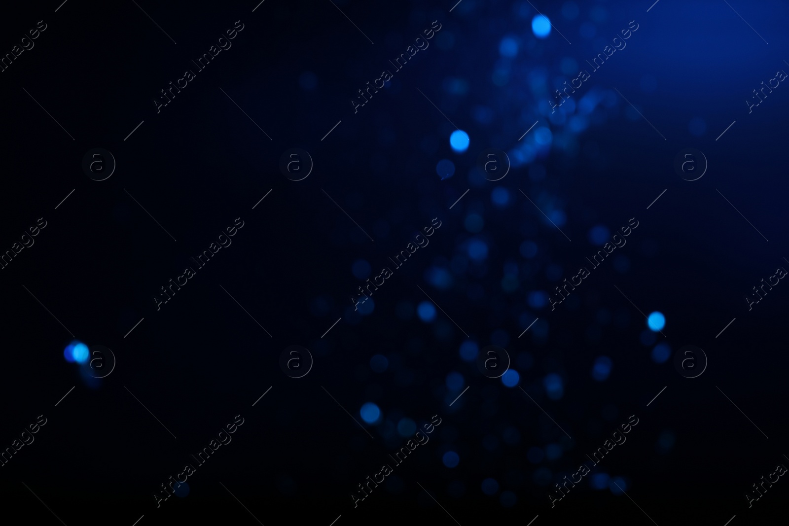 Photo of Blurred view of festive lights on blue background. Bokeh effect