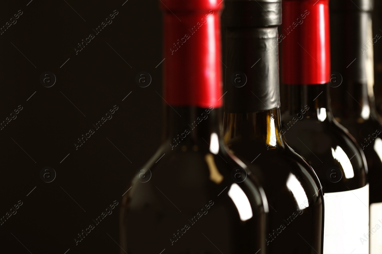 Photo of Bottles of different wines on dark background, closeup. Expensive collection