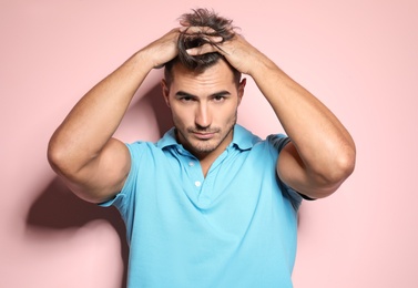 Young man with trendy hairstyle posing on color background