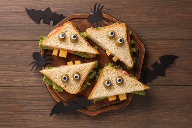 Tasty monster sandwiches and Halloween decorations on wooden table, flat lay