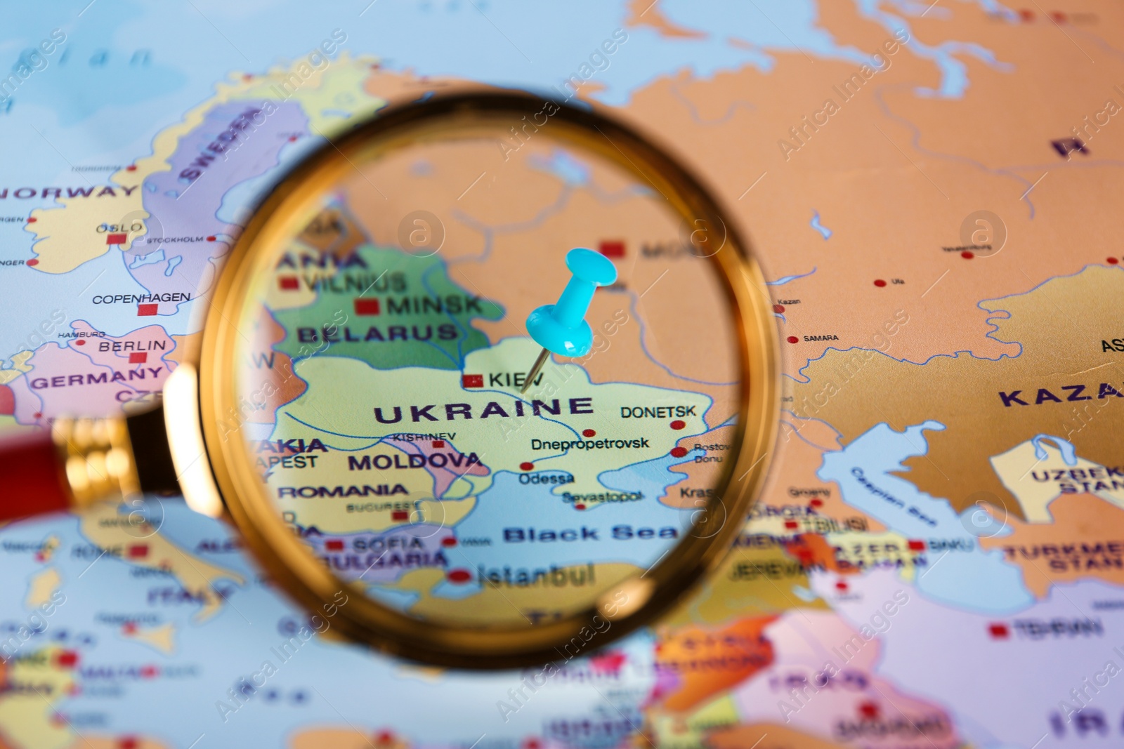 Photo of Looking at pinned Ukraine on map of Europe through magnifier, closeup. International relationships