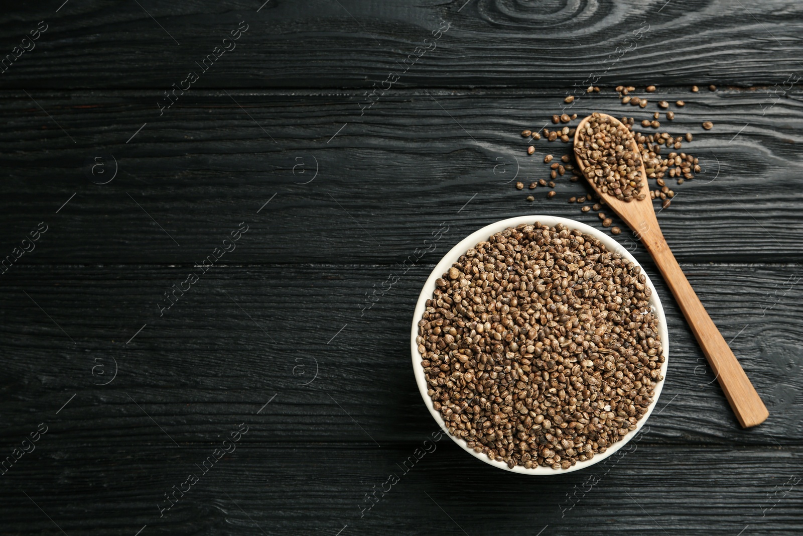 Photo of Ceramic bowl with chia seeds on black wooden table, flat lay and space for text. Cooking utensils