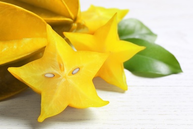 Delicious carambola fruits on white wooden table, closeup