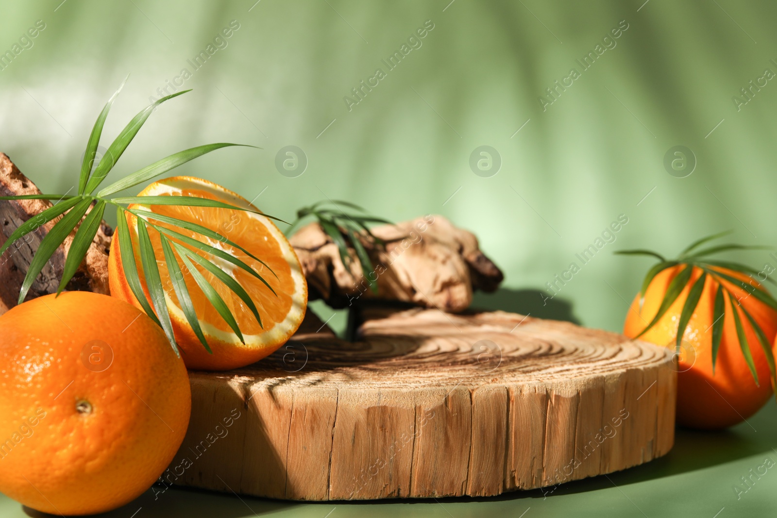 Photo of Tasty fresh oranges and leaves on green background, closeup. Space for text