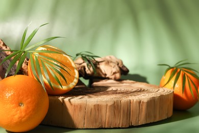 Tasty fresh oranges and leaves on green background, closeup. Space for text