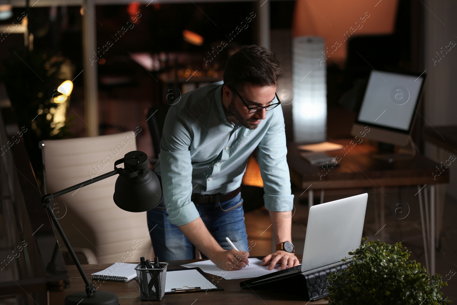 Photo of Young man working in office at night