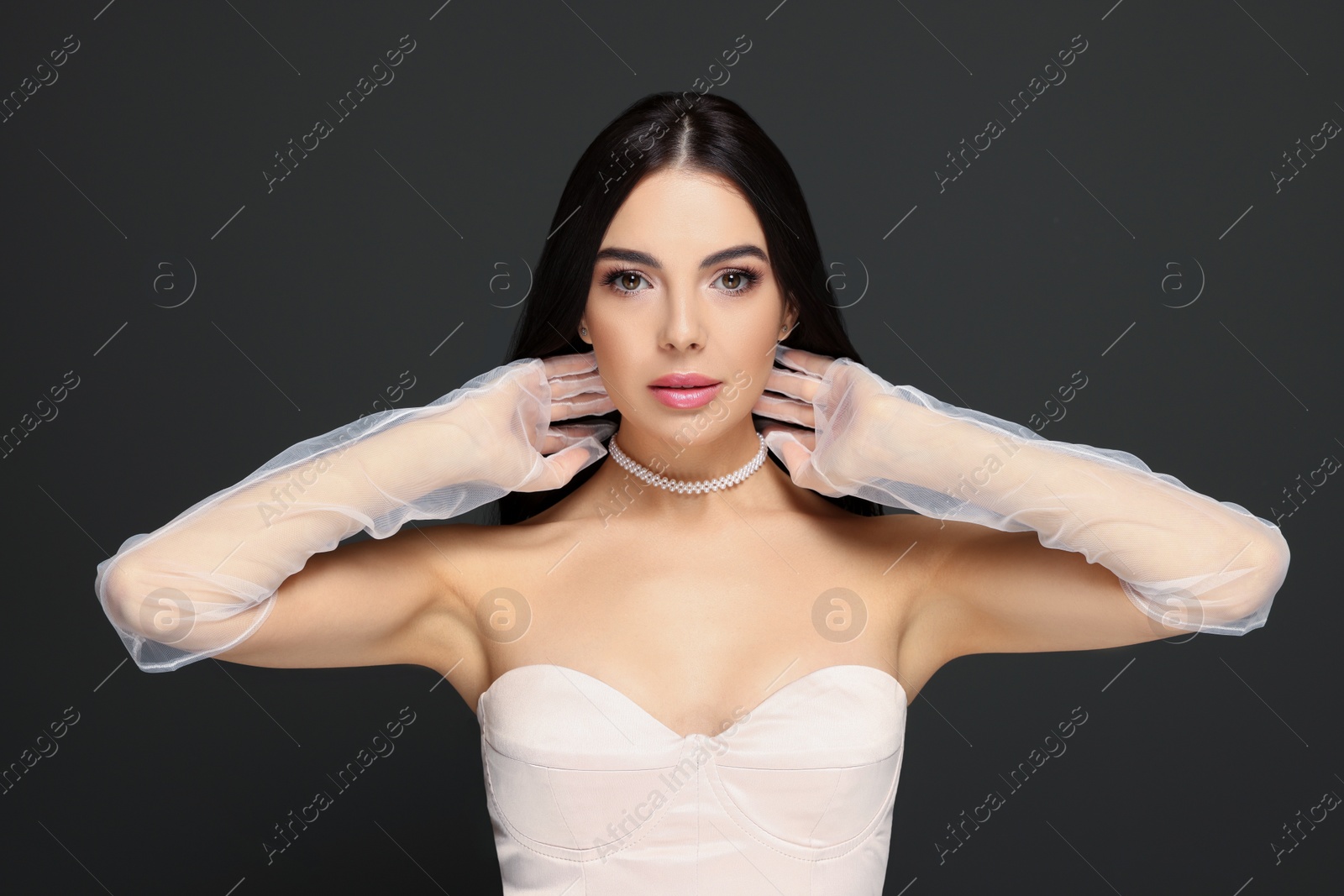 Photo of Portrait of beautiful young woman in evening gloves on black background