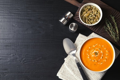 Photo of Flat lay composition with pumpkin cream soup in bowl on wooden background. Space for text