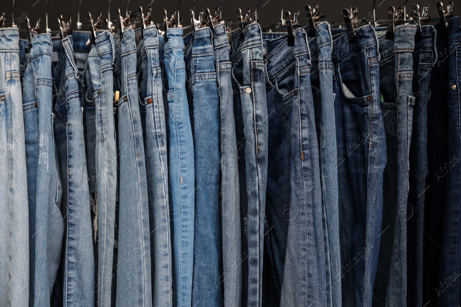 Photo of Rack with different stylish jeans, closeup view