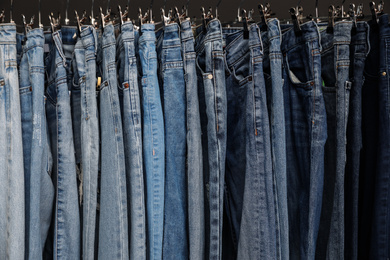 Photo of Rack with different stylish jeans, closeup view