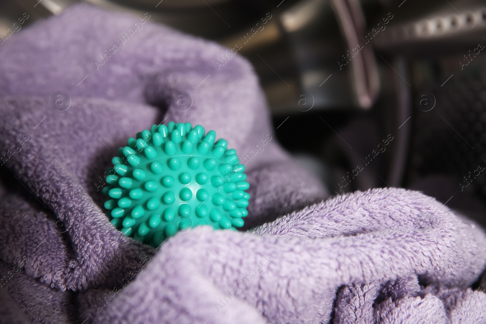 Photo of Green dryer ball and towel in washing machine drum, closeup. Space for text