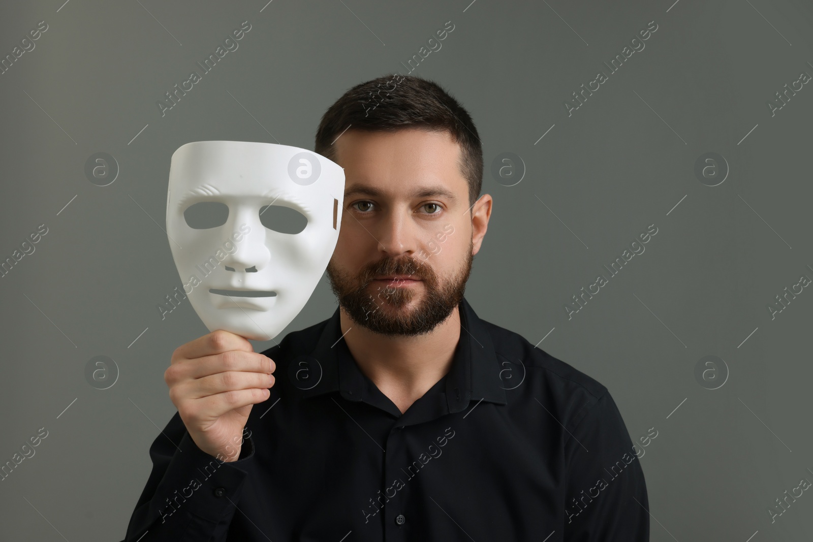 Photo of Multiple personality concept. Man with mask on grey background