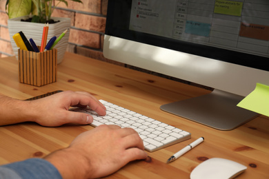 Young man using calendar app on computer in office, closeup