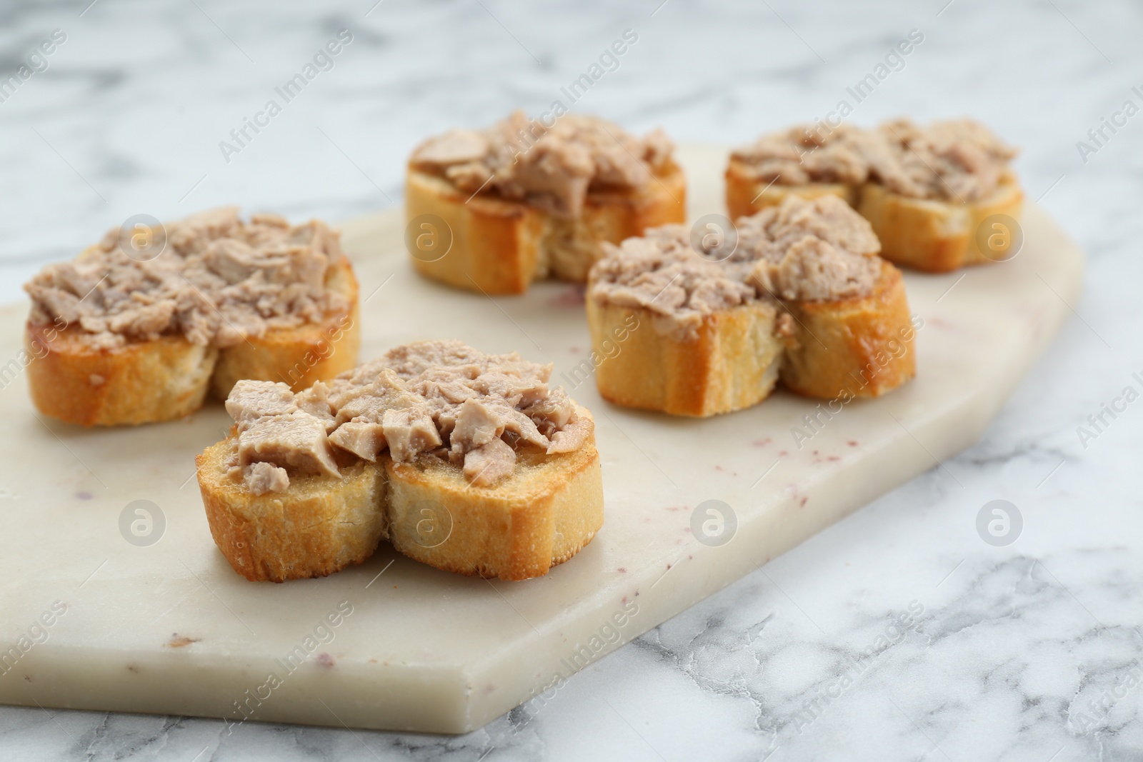 Photo of Tasty sandwiches with cod liver on white marble table