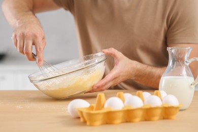 Photo of Man making dough at table in kitchen, closeup. Online cooking course