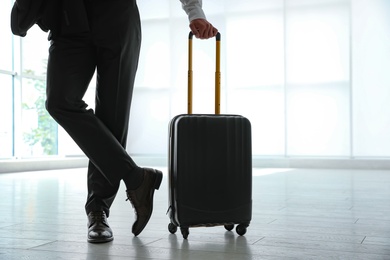 Businessman with black travel suitcase in airport
