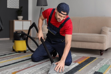 Photo of Mature man hoovering carpet with vacuum cleaner in living room