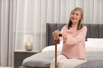 Photo of Mature woman with walking cane on bed at home