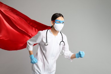 Photo of Doctor dressed as superhero posing on light grey background. Concept of medical workers fighting with COVID-19