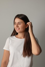 Photo of Happy young woman touching her hair on light background
