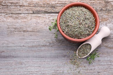 Bowl with scoop of dried and fresh thyme on wooden table, flat lay. Space for text