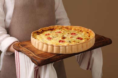 Photo of Woman with delicious homemade cheese quiche on beige background, closeup