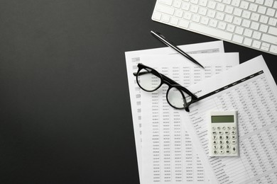 Accounting documents, calculator, glasses and computer keyboard on black table, flat lay. Space for text