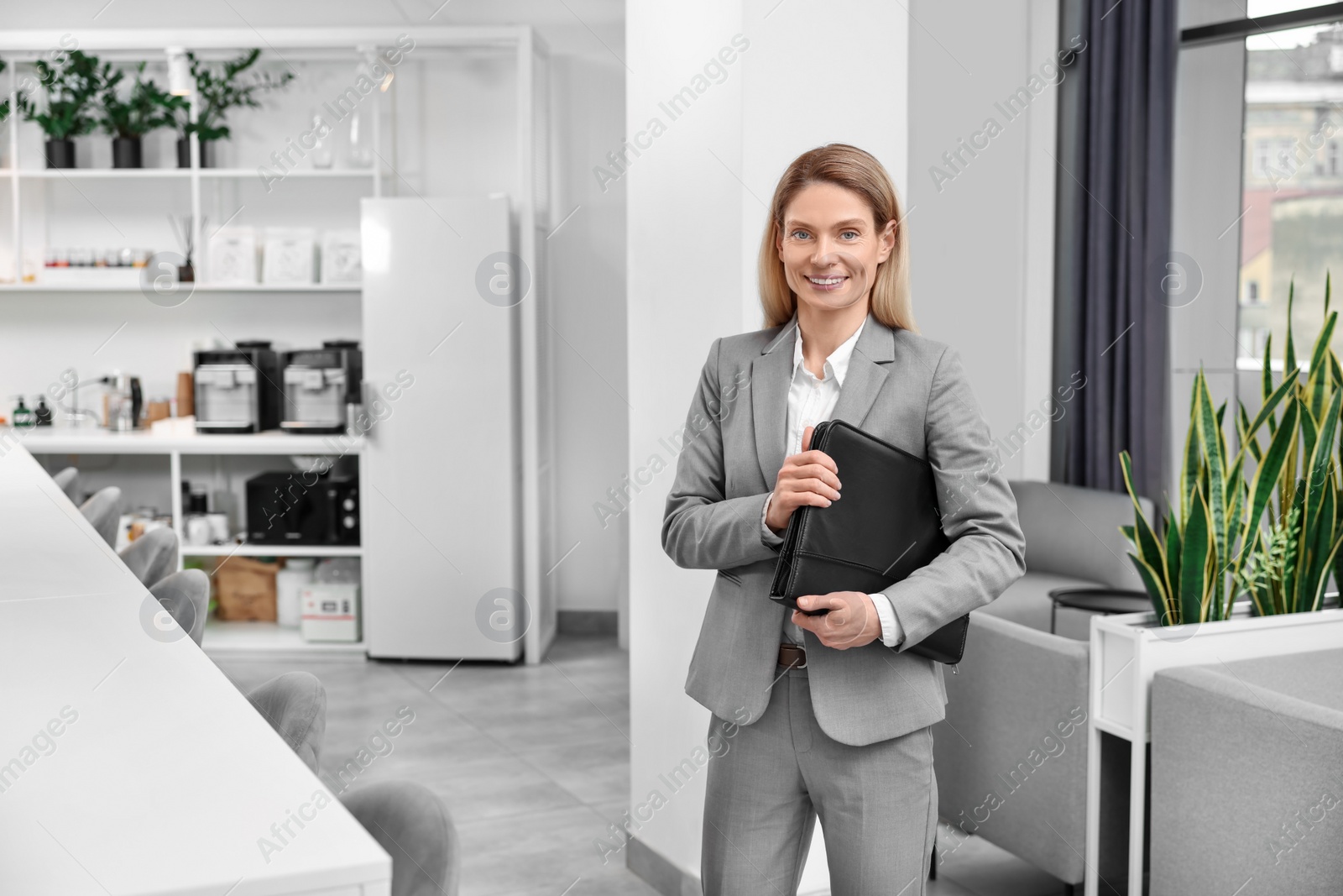 Photo of Happy real estate agent with leather portfolio indoors