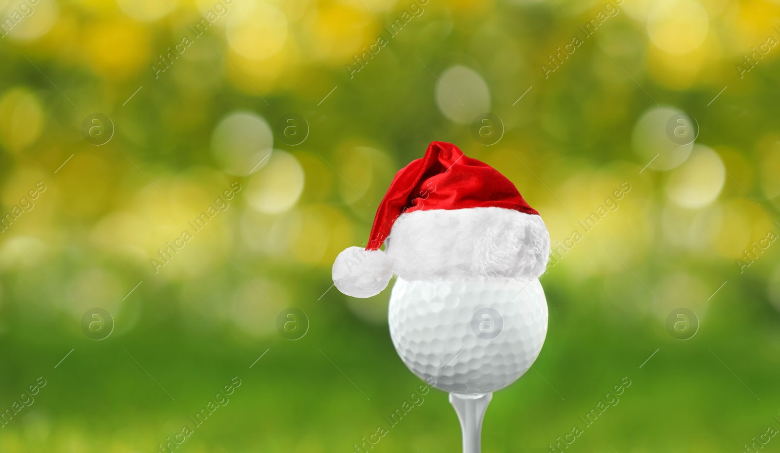 Image of Golf ball with small Santa hat on tee against blurred background