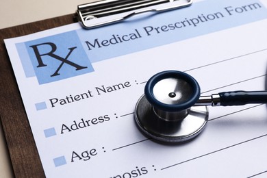 Photo of Clipboard with medical prescription form and stethoscope on beige background, closeup