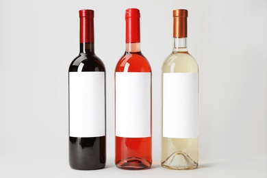 Photo of Bottles of delicious wines with blank labels on white background