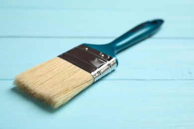 New paint brush on blue wooden table, closeup. Space for text