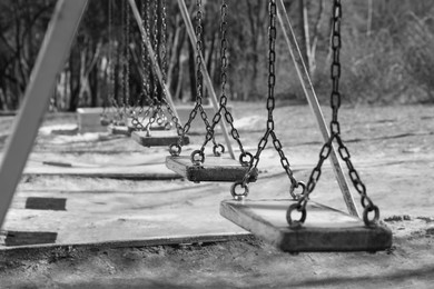 Photo of Wooden swings in park. Black and white effect